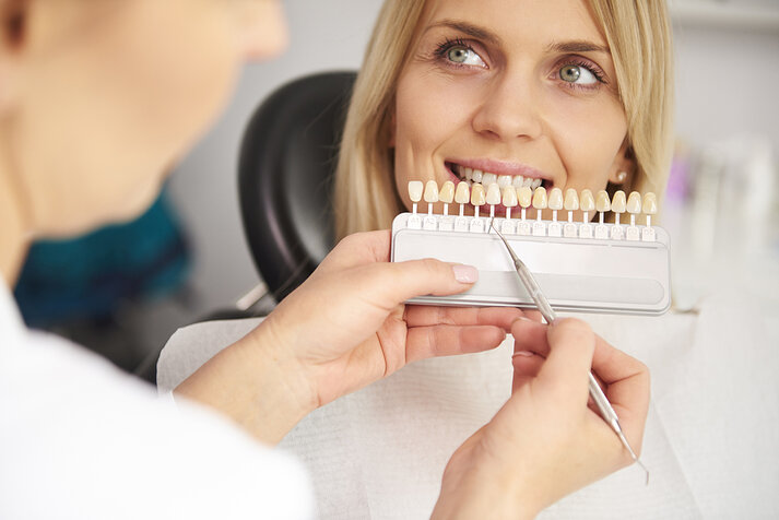 Part of dentist choosing color teeth from palette  